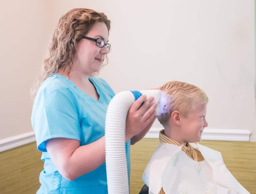 child getting lice treatment from clinic using a flosonix device